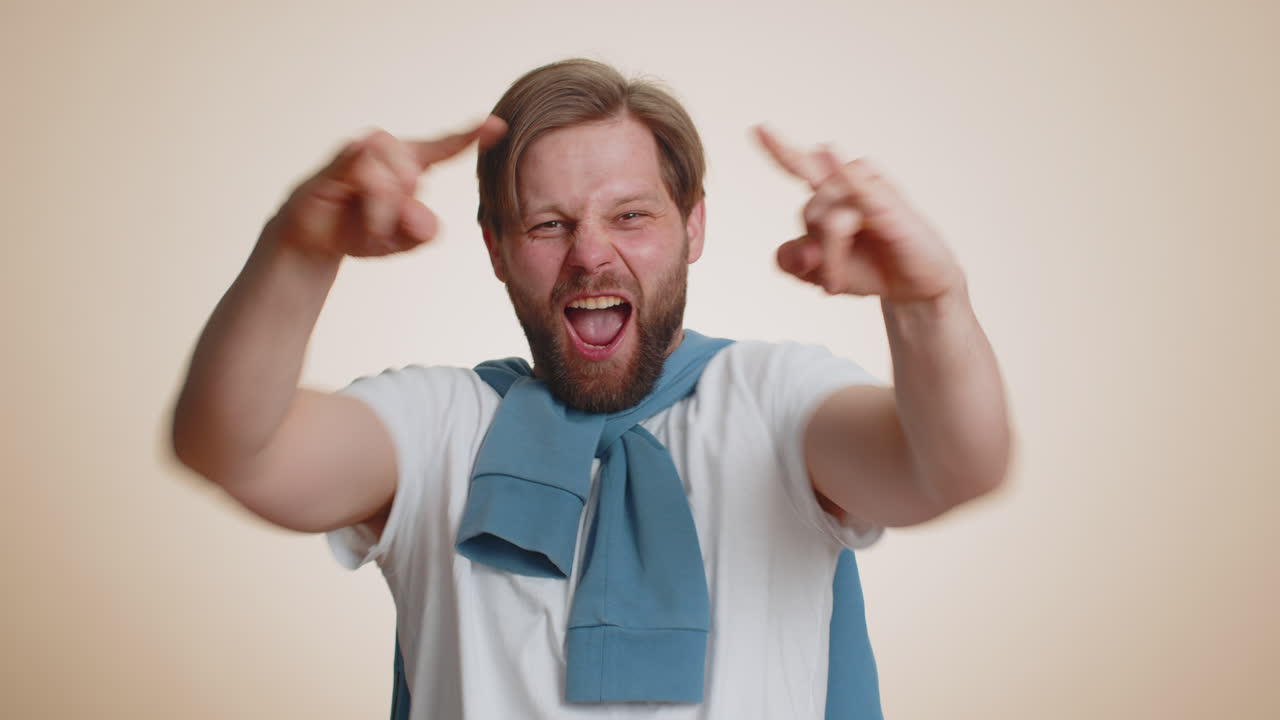 Caucasian man showing rock n roll gesture by hands cool sign crazy expression dancing celebrating