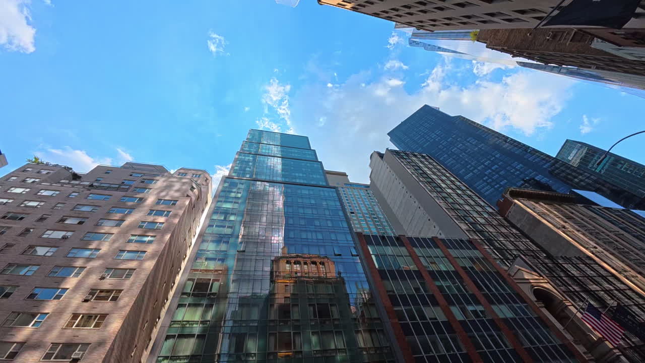 New York, USA, 1 August 2025: Glass skyscrapers reflecting the blue sky in Manhattan. Reflection of clouds and sky in tall glass skyscrapers in Midtown Manhattan