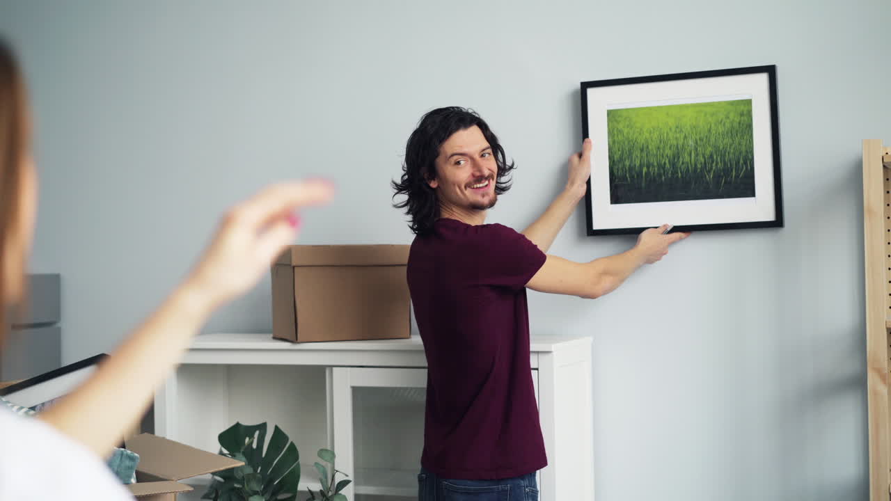 una pareja colgando un cuadro.