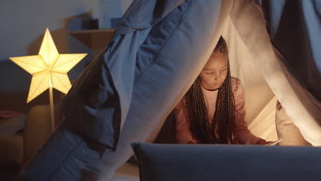 little girl reading book in pillowfort