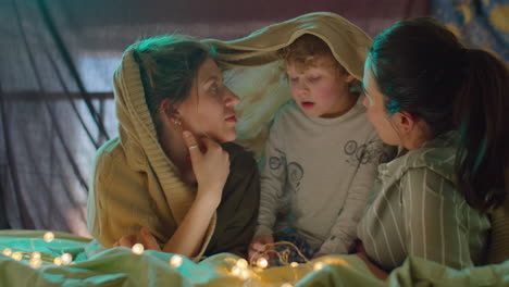 lesbian couple talking with kid on bed