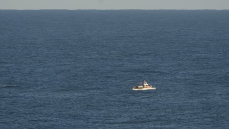 a small fishing boat sailing in the blue ocean