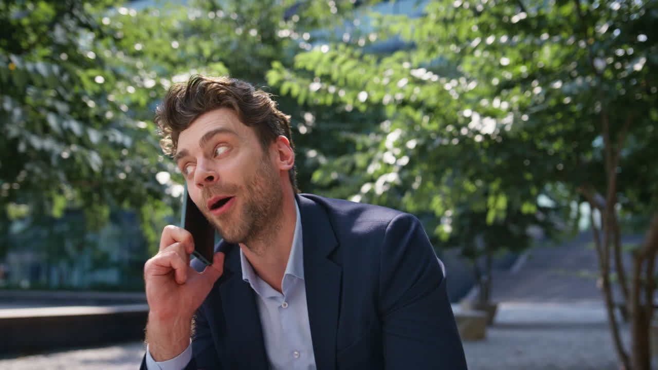 기쁜 남자가 드폰으로 얘기하고 빛이 은 거리에 앉아 있습니다. 남자가 전화하고 있습니다.