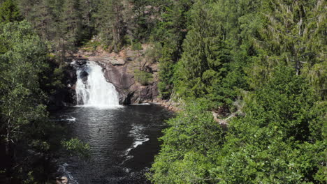 kaja waterfall or kajafoss in green forest of norway, aerial descent