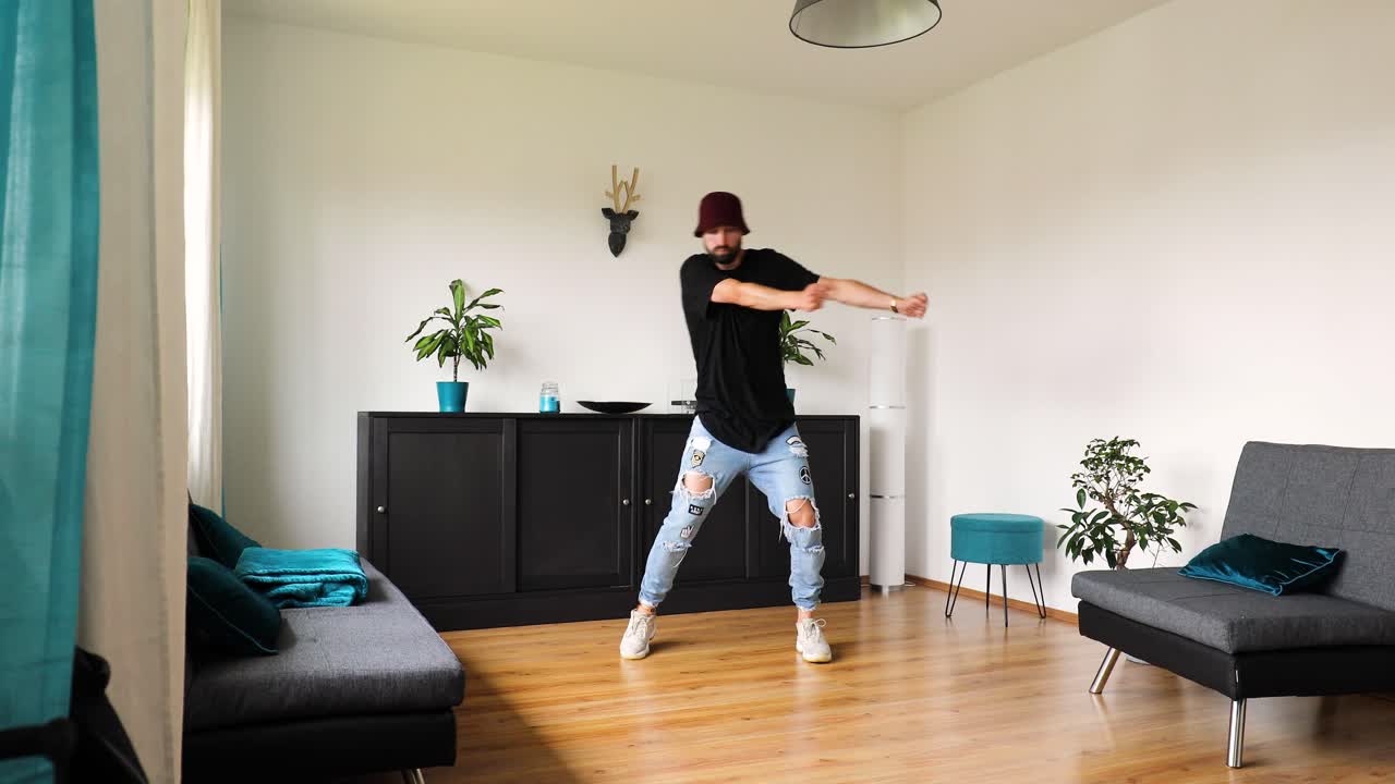 young man dances in the living room and trains his dance steps