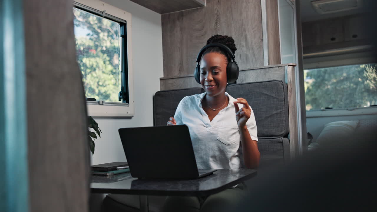 Happy Young Woman Laughing While Using Laptop and Headphones in RV