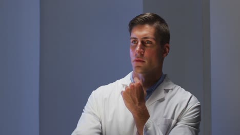 Handsome-caucasian-male-doctor-wearing-lab-coat-looking-at-information-using-virtual-digital-interfa