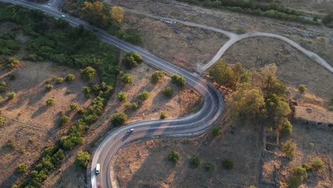 Timelapse,-aerial-drone-view-pulling-away,-curved-road-busy-with-cars-driving