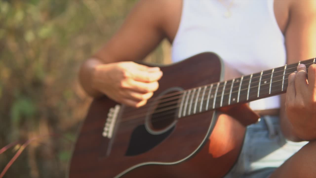 tiro desenfocado acercándose a una chica morena tocando una guitarra