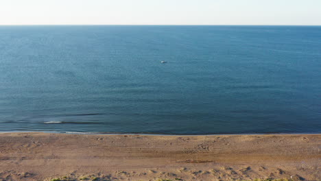 Pequeño-Barco-En-El-Tranquilo-Mar-Mediterráneo-A-Lo-Largo-De-La-Vista-Aérea-De-La-Playa