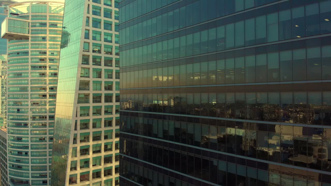 drone ascendiendo junto a edificios altos reflexión en blanco y negro en las ventanas luz dorada
