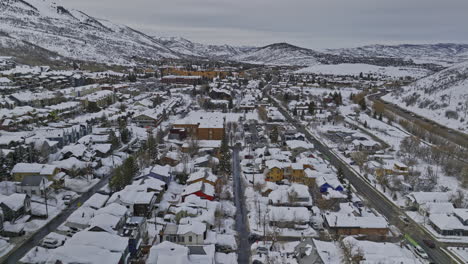 Park-City-Utah-Luftbild-V77-Überflug-Entlang-Der-Hauptstraße-Quer-Durch-Das-Stadtzentrum,-Aufnahme-Von-Gebäuden-Und-Häusern,-Die-Mit-Unberührtem-Schnee-Bedeckt-Sind,-Und-Winterlicher-Berglandschaft-–-Aufgenommen-Mit-Mavic-3-Cine-–-Februar-2023