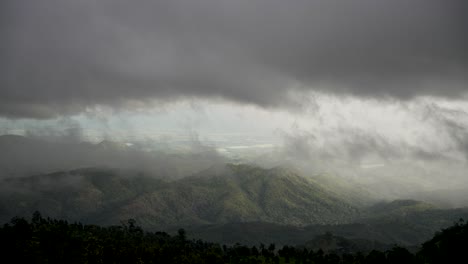 con vistas a un verde valle con denso bosque envuelto por dramáticas nubes y niebla.