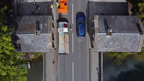 top down of an old stone bridge with toll buildings incorporated, traffic filtering through with roadworks taking place