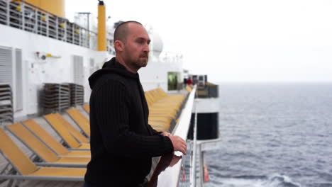 Man-stands-on-deck-of-cruise-ship-not-feeling-well