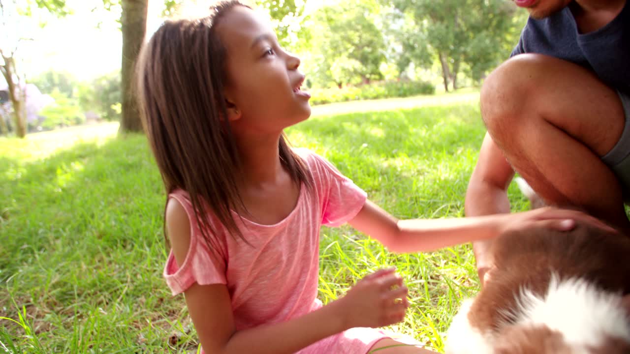 una joven afroamericana de cabello largo y morena acurrucada acurrucando a un cachorro.