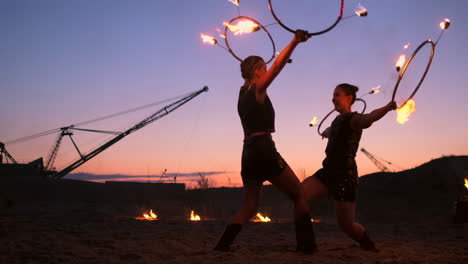 professional artists show a fire show at a summer festival on the sand in slow motion. fourth person acrobats from circus work with fire at night on the beach