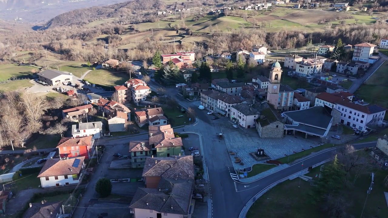 Il borgo storico di Morfasso si estende nell'alta Val d'Arda a Morfasso, Piacenza, Emilia-Romagna, Italia, circondato da dolci colline dell'Appennino settentrionale e terreni agricoli rurali, ripresa aerea con drone in picchiata