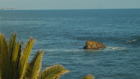 surfers in ocean waiting for waves near cliff