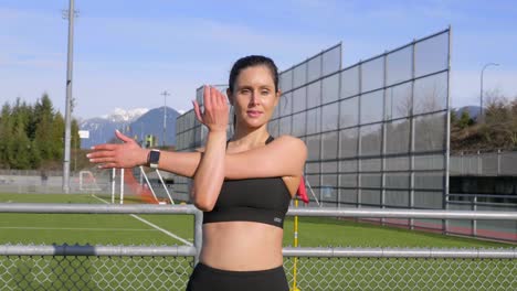 joven atlética estirando el brazo antes de hacer ejercicio al aire libre