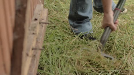 gardener with fork digging grass outside shed