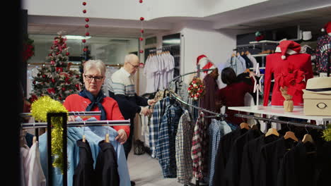 customers roaming around busy clothing store decorated with christmas ornaments during winter holiday season. clients shopping for gifts during xmas promotional sales in fashion boutique