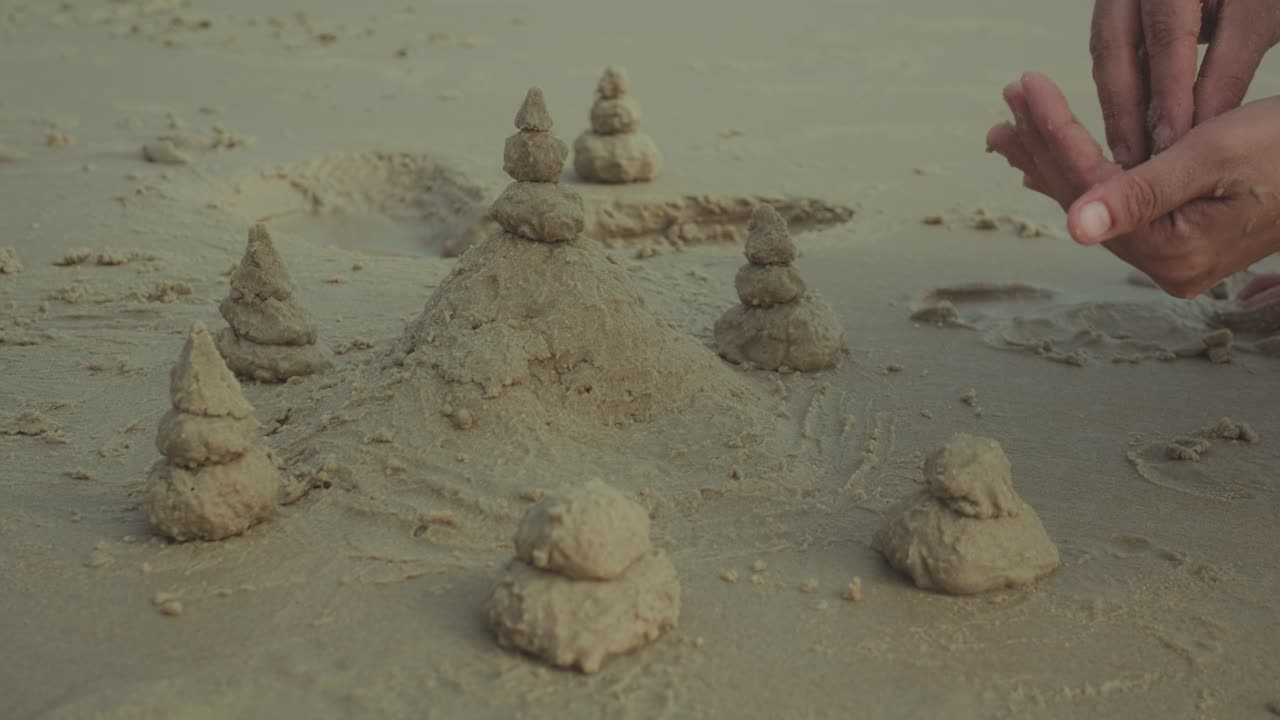 Vista aproximada de pequenas torres e formas de areia na areia molhada da praia, uma cena costeira criativa e divertida.