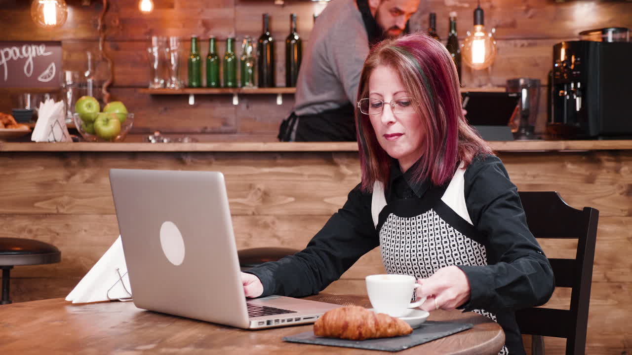 mujer trabajando en una computadora portátil en un café