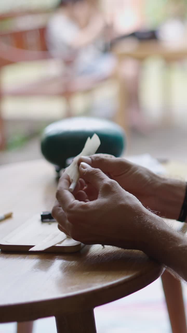 Hands rolling paper on wooden table