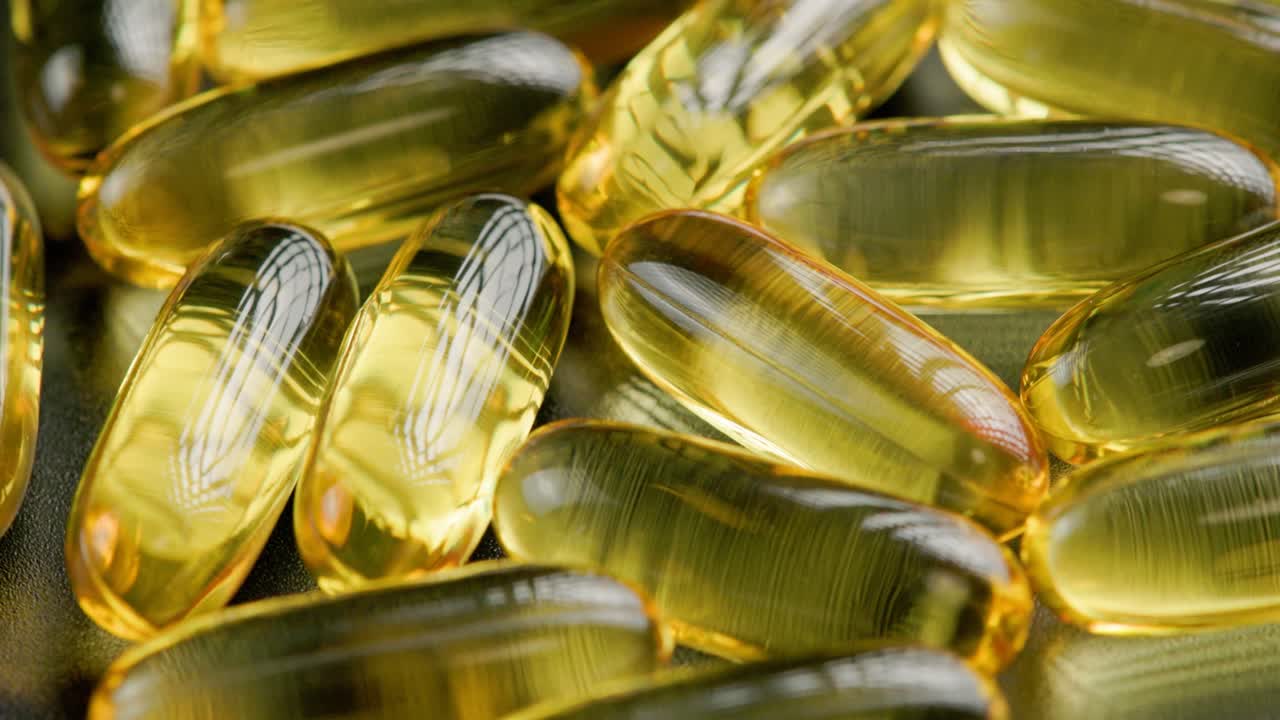 pastillas transparentes doradas con medicamento líquido giratorio, primer plano de cuadro completo