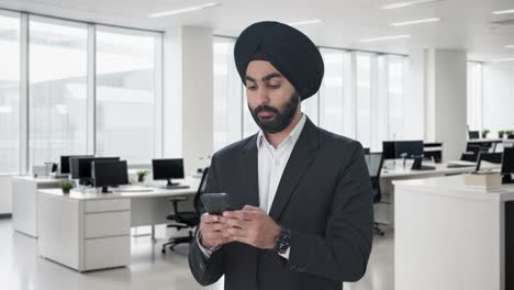 serious sikh indian businessman texting someone