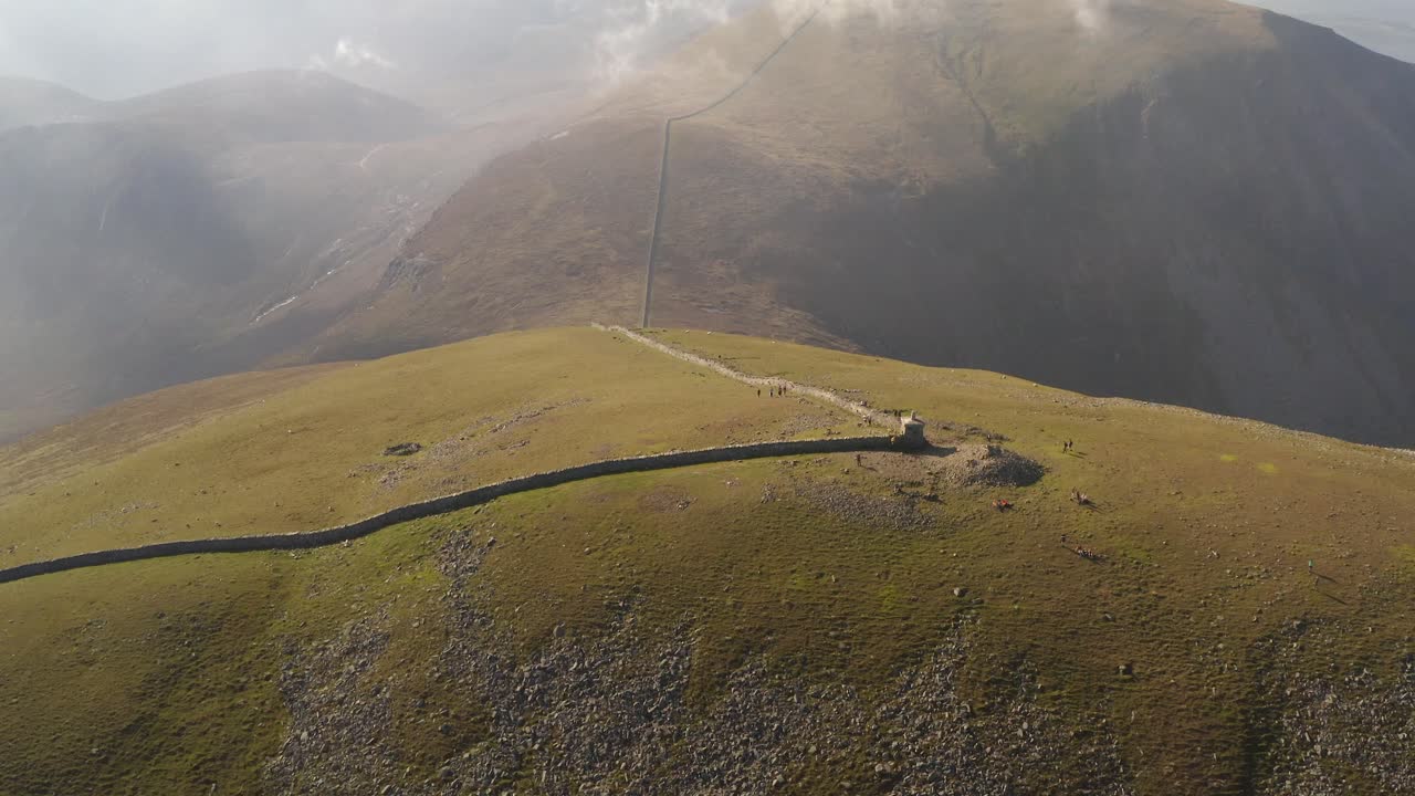 Ascend aerial at Slieve Donard's peak revealing a the majestic views