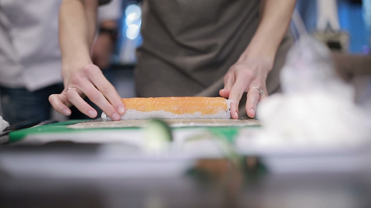 Woman Chef Filling Japanese Sushi Rolls. Hands of woman chef filling japanese sushi rolls with rice on a nori seaweed sheet