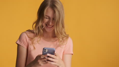 una mujer caucásica usando un teléfono inteligente y siendo sorprendida por la cámara.