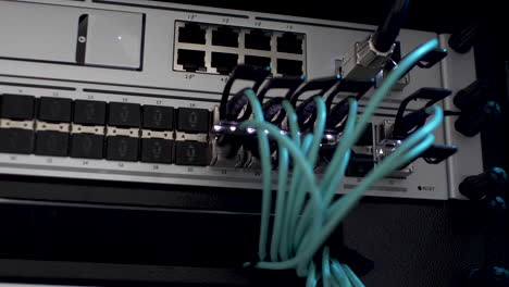 lan cables plugged in network server rack with white blinking lights