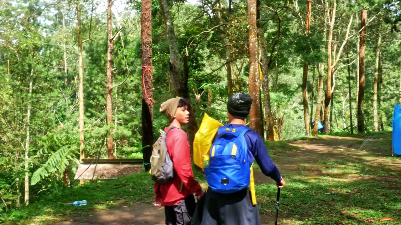 Adventurous hikers with backpacks explore lush forest trails near campsite embracing nature's beauty and outdoor exploration