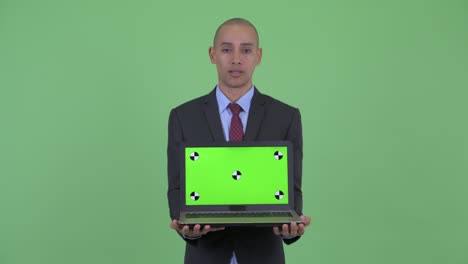 stressed bald multi ethnic businessman showing laptop