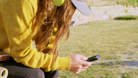 Seitenansicht-Einer-Jungen-Kaukasischen-Frau,-Die-Am-Strand-Musik-Hört-Und-Ihr-Mobiltelefon-Benutzt,-4k