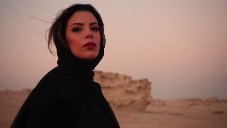 girl looking straight at the camera with innocent eyes holding a black scarf in her hands flying towards the camera to cover the lens in the fossil dunes uae dubai abu dhabi