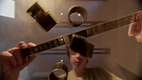 man inspecting old film strips and reels