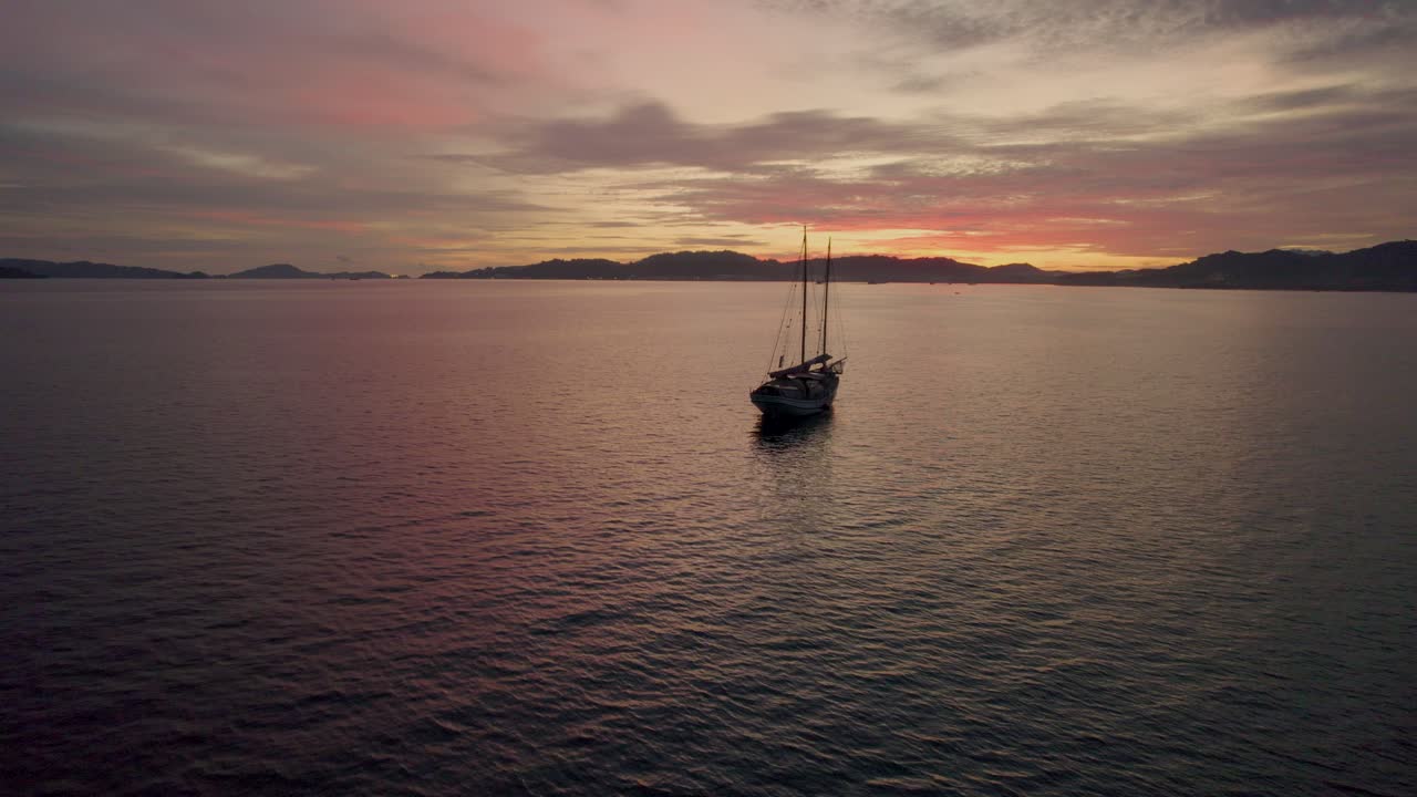 Vista panoramica di una tradizionale barca da pesca in un oceano sereno al tramonto vicino alla città di Kuah, sull'isola di Langkawi, Malesia.