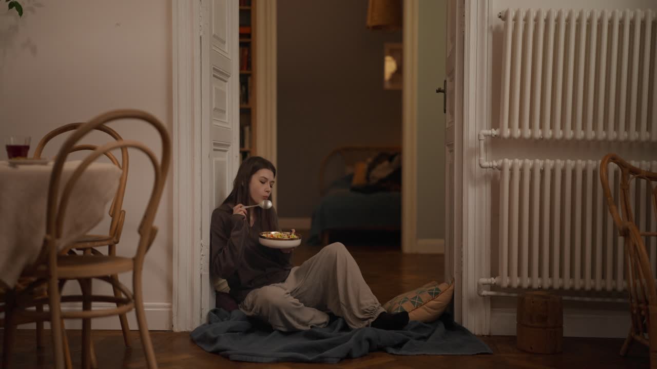 A woman sitting in a doorway eating a meal