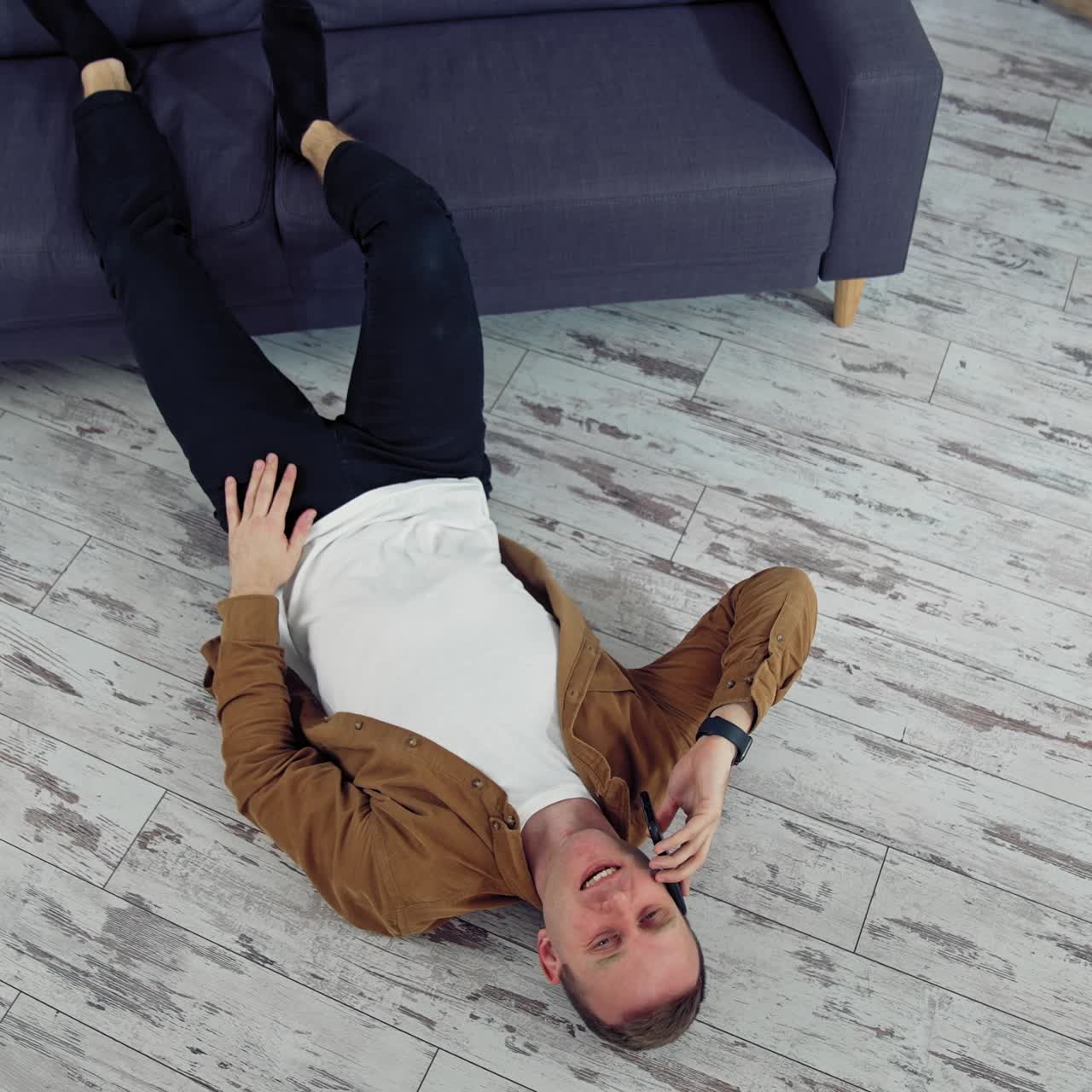 Man relaxing at home on floor. Young man relaxing on the floor and talking on mobile phone