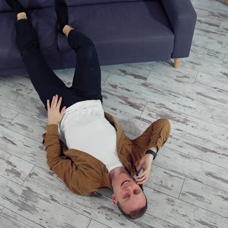 man relaxing at home on floor. young man relaxing on the floor and talking on mobile phone