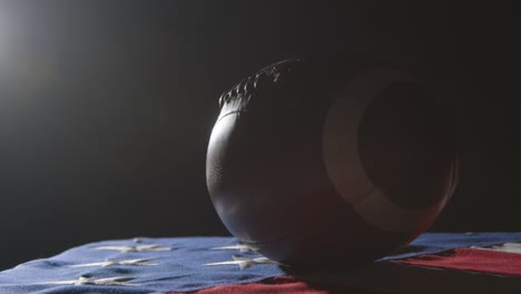 low key lighting studio shot of american football on stars and stripes flag 3