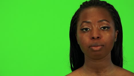 a young black woman looks to the camera - face closeup - green screen studio