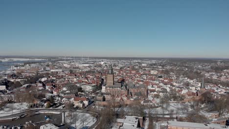 Medieval-Hanseatic-Dutch-tower-town-Zutphen-in-the-Netherlands-covered-in-snow-with-historic-heritage-buildings-and-river-IJssel-passing-by-in-the-background-seen-from-above