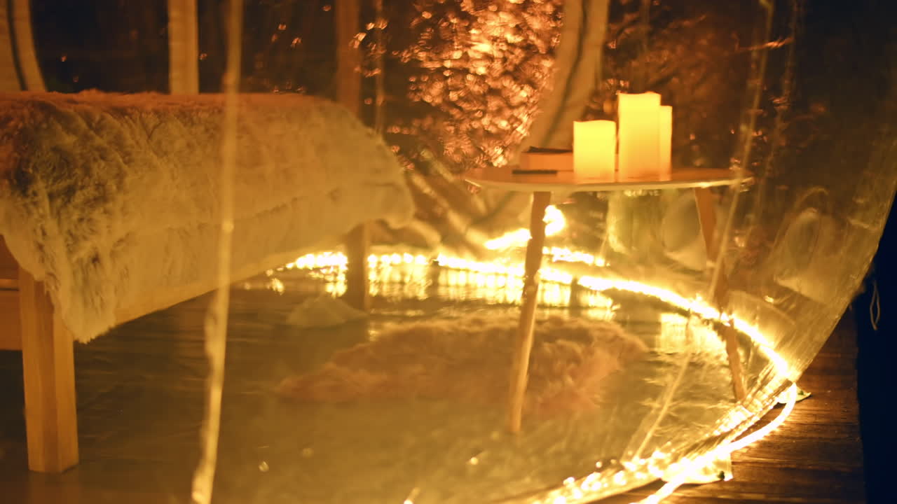 Tenda a bolla trasparente in un glamping di notte, interni con illuminazione gialla