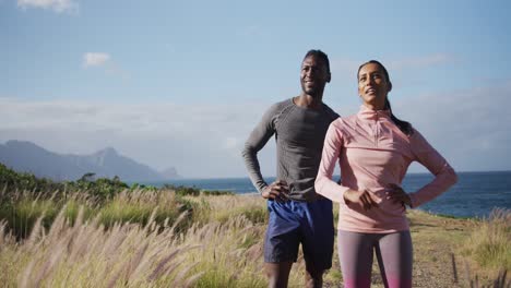 Diverse-fit-couple-talking-and-laughing-in-a-field-whiel-exericising-in-countryside