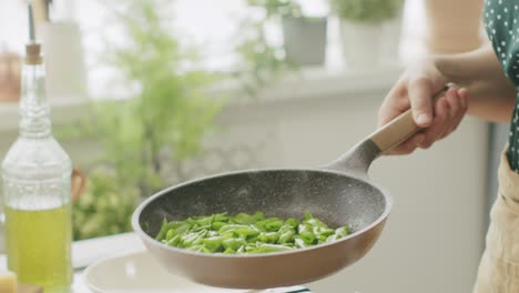 Unrecognizable-cook-frying-green-beans-in-pan